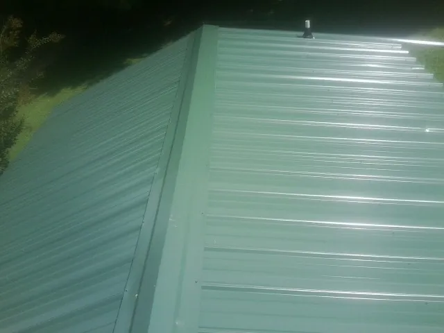 New green metal panels meeting at the ridge of a roof — Flat Roof Repair work by our crew in South Richmond Hill