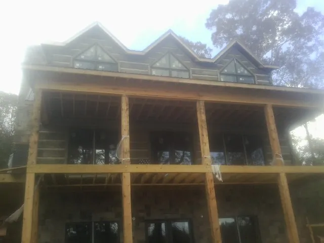 Dormers and porch framing on a large log home under construction — Roof Coating work by our crew in South Richmond Hill