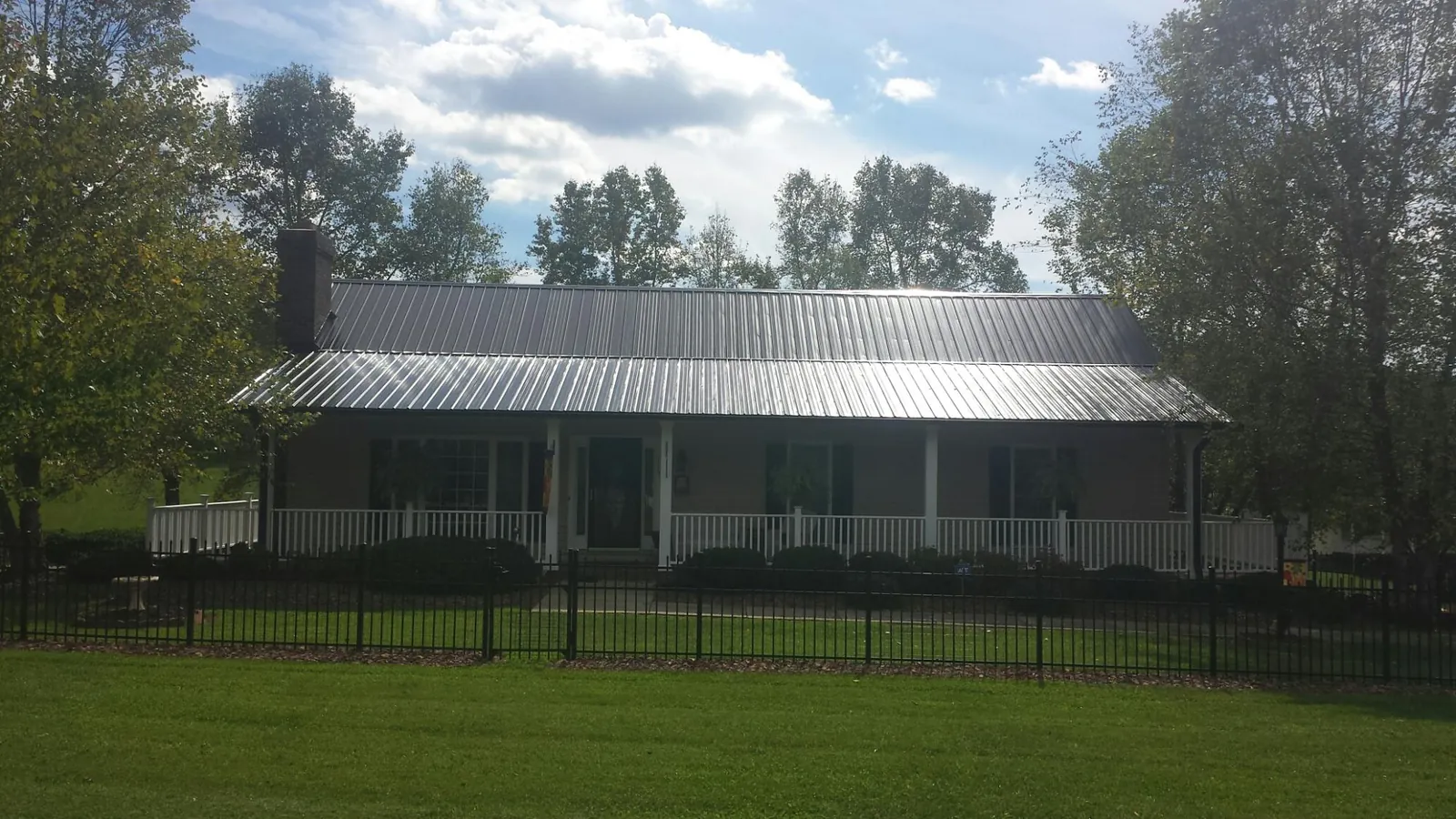 Gray metal roof on a brick ranch with a full width front porch — Gutter Guard Installation work by our crew in South Richmond Hill